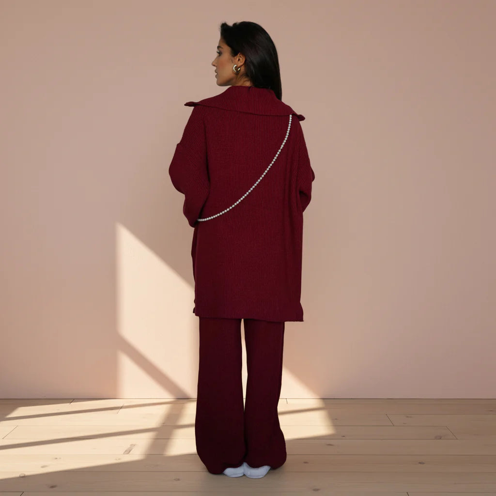 Person wearing a burgundy outfit with a matching coat and pants on a plain background