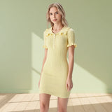 Woman wearing a yellow dress with ruffled details on a gray background