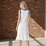 Woman wearing a white dress with blue accents on a gray background