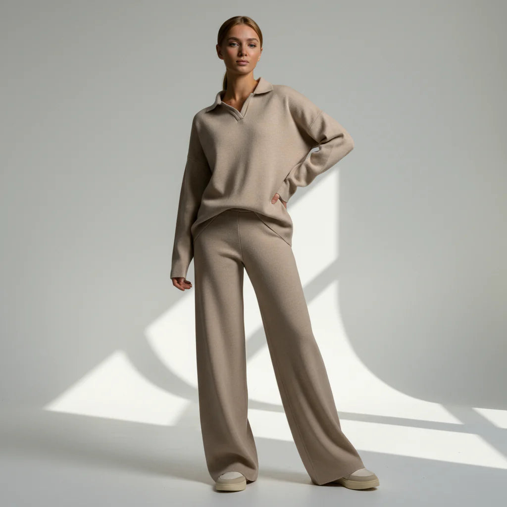 Woman wearing a beige sweater and pants standing against a neutral background