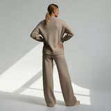 Woman wearing a beige outfit standing in a well-lit room with a neutral background