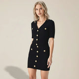 Woman wearing a black dress with gold buttons on a gray background