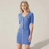 Woman wearing a blue dress with gold buttons on a plain background