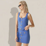 Woman wearing a blue dress with gold buttons on a gray background