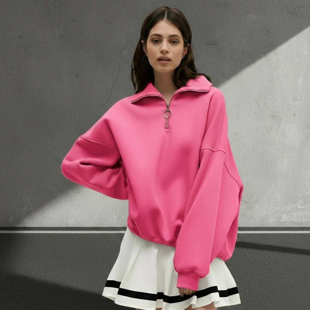Woman wearing a pink oversized sweatshirt with a white skirt on a gray background