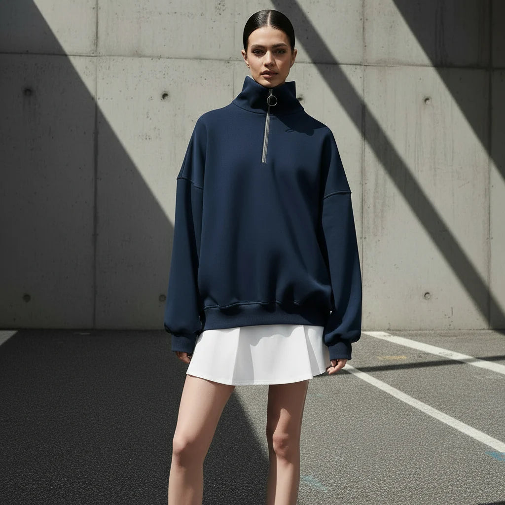 Person wearing a navy blue high-neck sweatshirt on a gray background