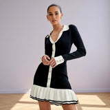 Woman wearing a black and white dress with long sleeves on a gray background