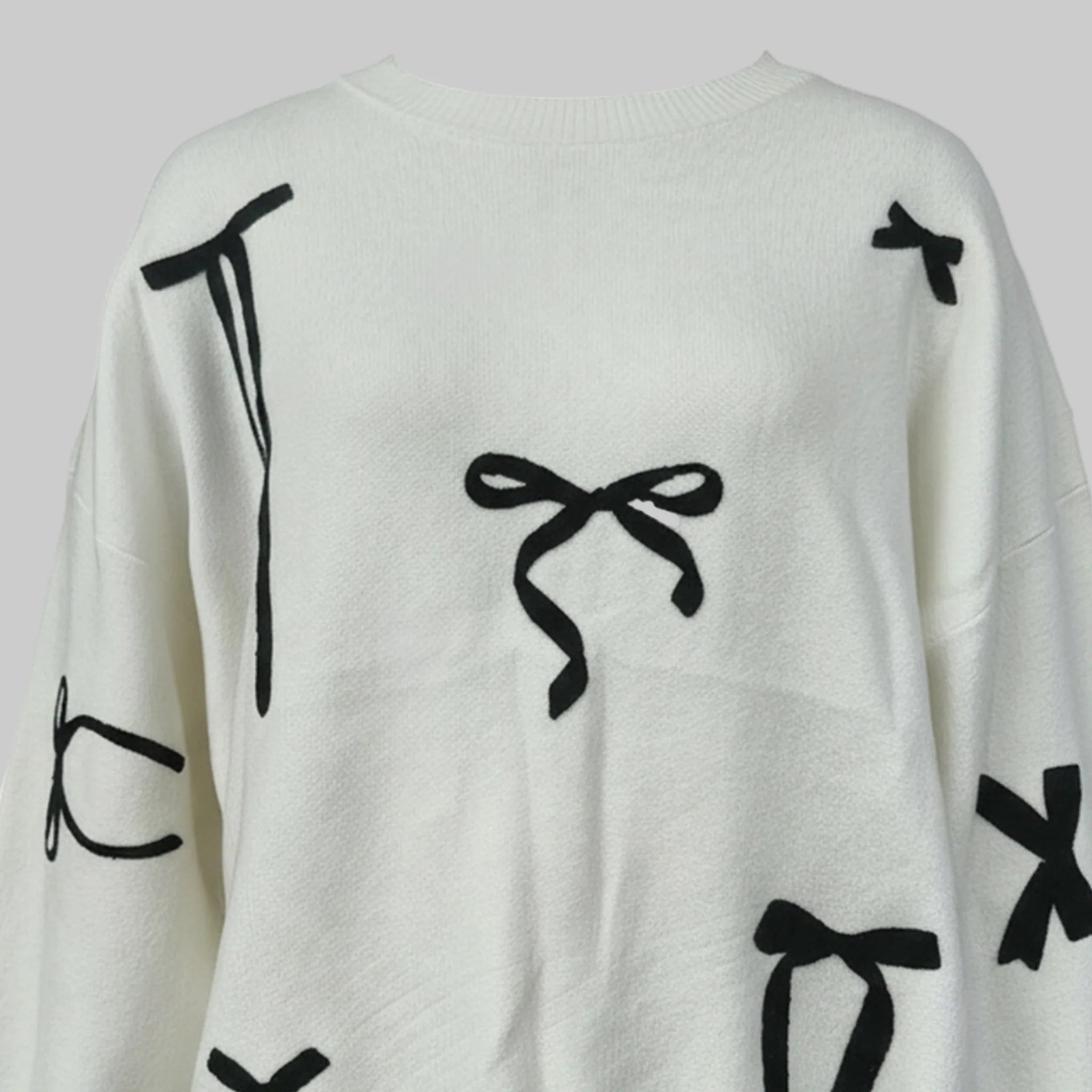 White sweater with black bow patterns on a white background
