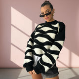 Woman wearing a black and white striped sweater against a pink wall.