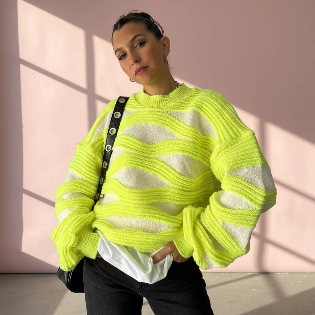 Person wearing a bright yellow and white striped sweater against a pink wall.