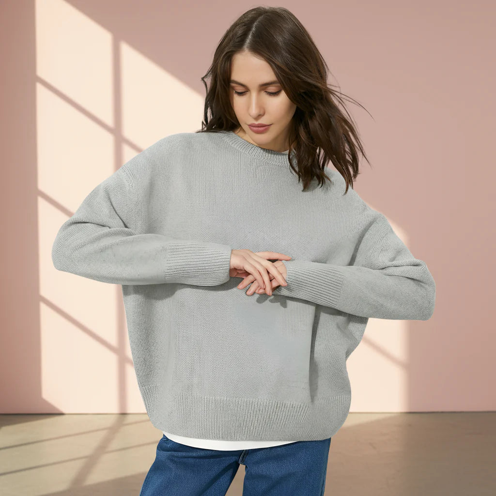 Woman wearing a gray sweater on a plain background