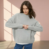 Woman wearing a gray sweater on a plain background