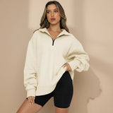 Woman wearing a beige oversized hoodie and black shorts on a gray background
