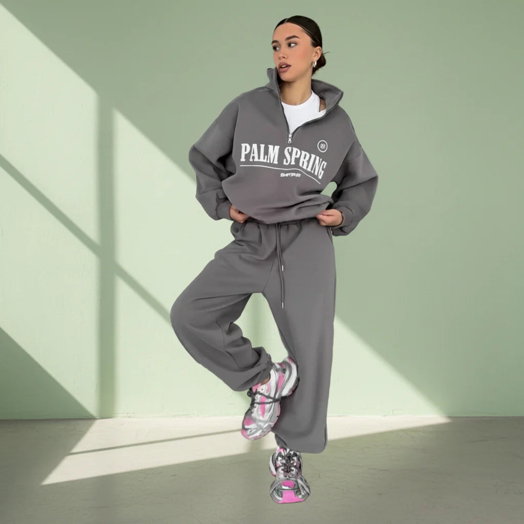 Person wearing a gray 'Palm Spring' tracksuit on a light gray background