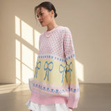 Woman wearing a colorful sweater with bow patterns in a softly lit room.