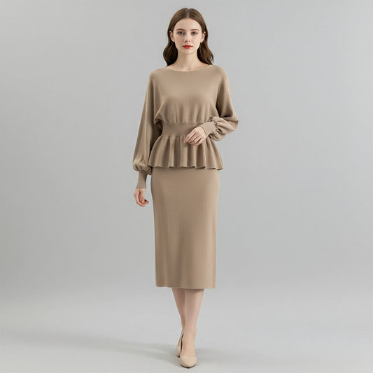 Woman wearing a beige peplum top and skirt on a gray background