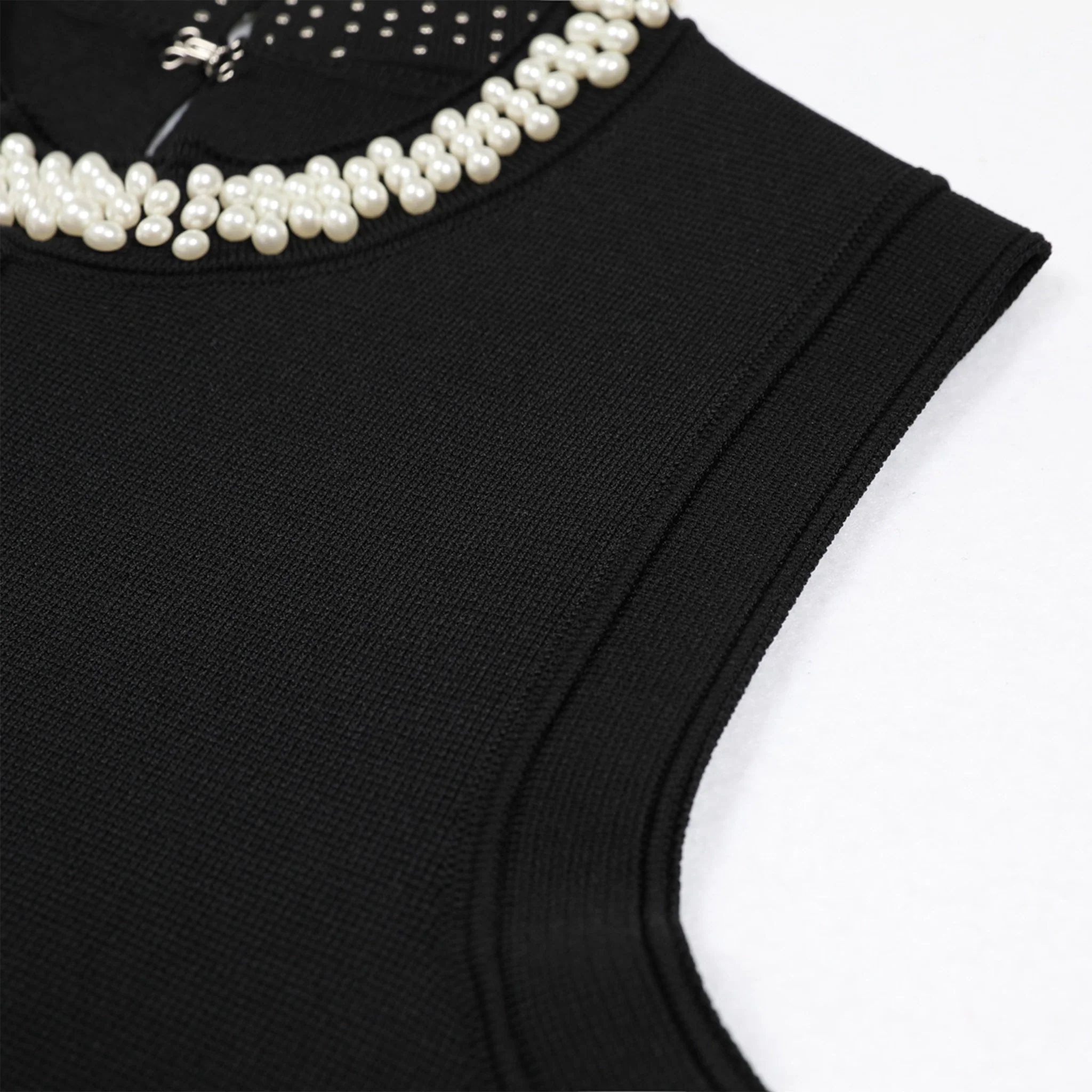 Black sleeveless top with pearl embellishments on a white background