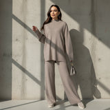 Woman wearing a beige outfit with a matching handbag on a gray background