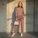 Woman wearing a brown outfit with a beige handbag on a gray background