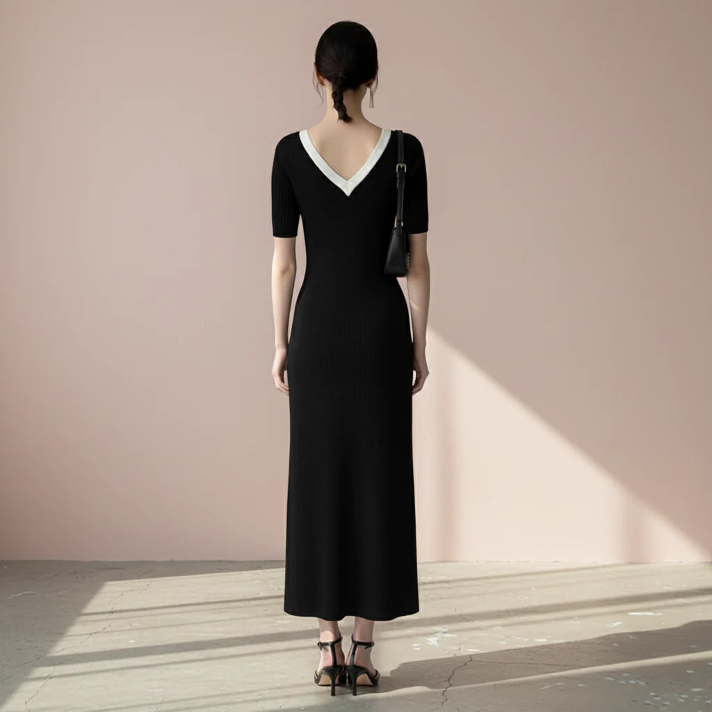 Woman wearing a black dress with a white collar on a gray background