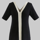 Black dress with white trim on a white background