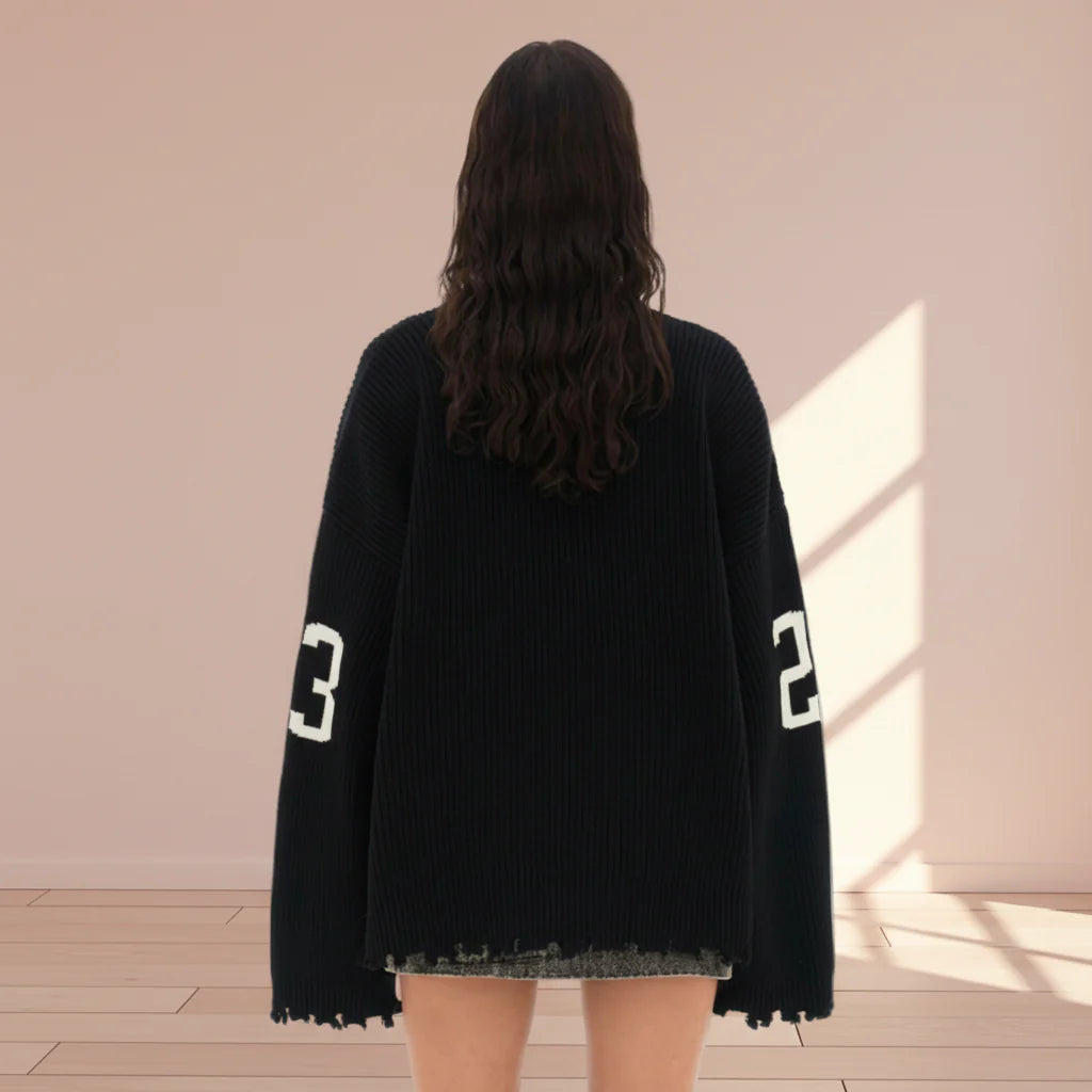 Person wearing a black oversized sweater with numbers on a plain background